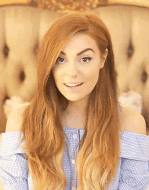 a woman with long red hair is wearing a blue and white checkered off the shoulder top