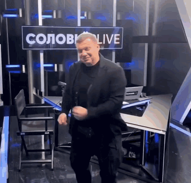 a man in a suit is dancing in front of a sign that says ' colov live '
