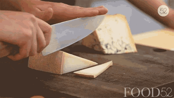 a person is cutting a piece of cheese on a wooden cutting board with the words food52 on the bottom