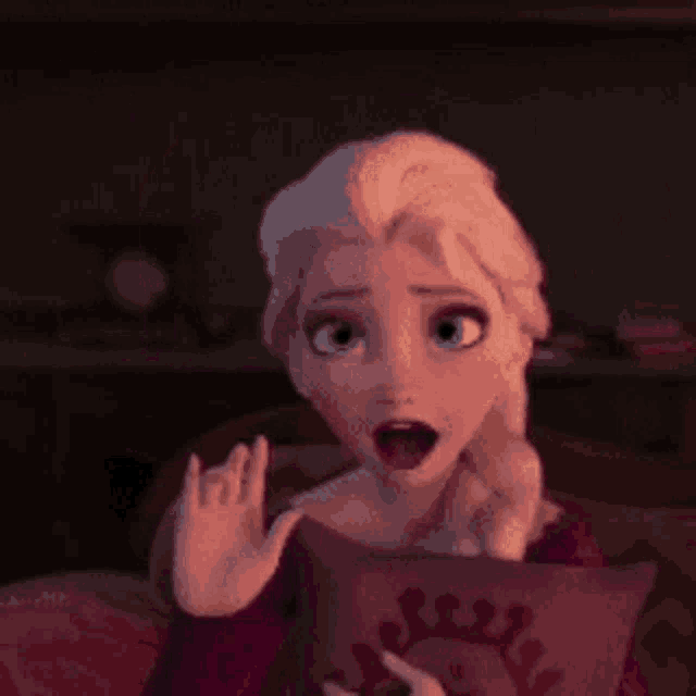 elsa from the movie frozen is sitting on a couch holding a pillow .
