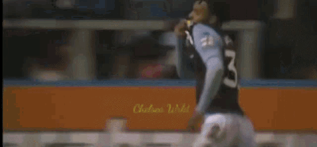 a soccer player is running in front of an energy drink banner