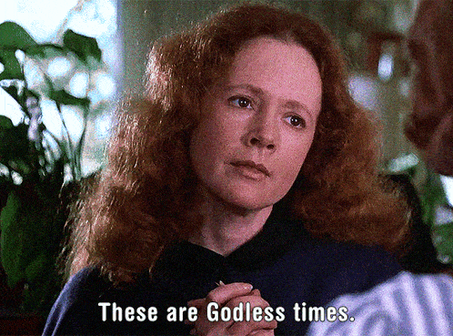 a woman with red hair is talking to a man and says " these are godless times "