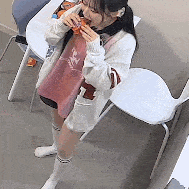 a girl wearing a sweater with the number 7 on it is eating a snack