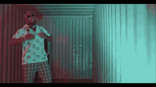 a man in a white shirt and plaid shorts is standing in a hallway .