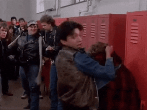 a group of people are standing in front of red lockers .