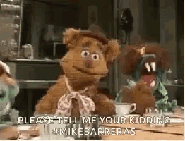 fozzie bear from sesame street is sitting at a table with a cup of coffee and a cup of tea .