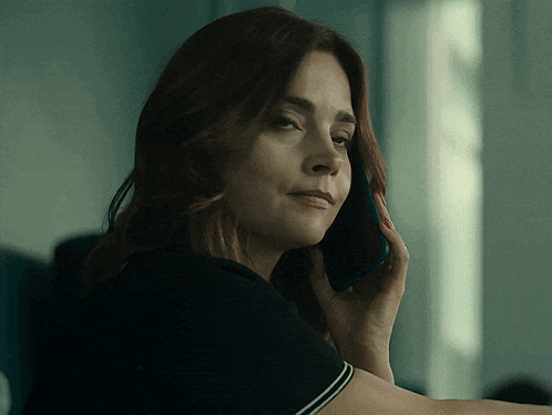 a woman in a black shirt is talking on her phone