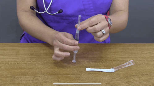 a nurse in a purple scrub is holding a syringe