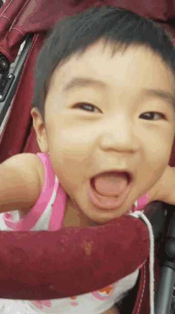 a baby is sitting in a stroller with his tongue out