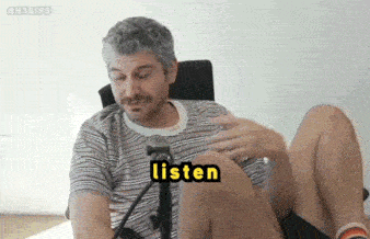a man is sitting in a chair with his legs crossed and the word listen written on his chest .