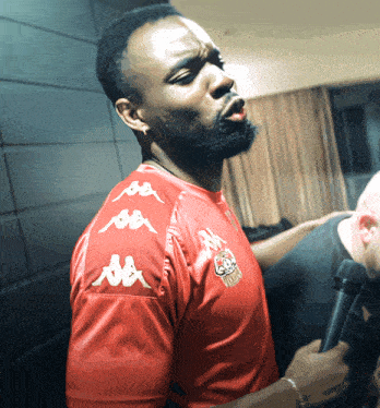 a man wearing a red shirt with kappa on the sleeves