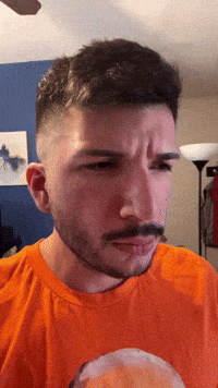 a man with a beard and mustache wearing an orange shirt