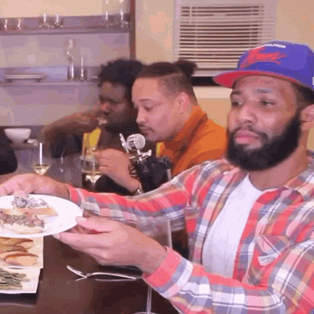 a man in a plaid shirt is holding a plate of food in front of a group of men