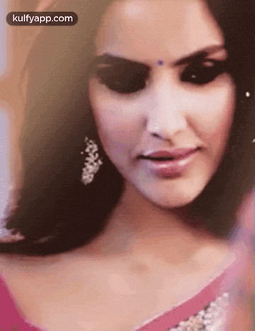 a close up of a woman 's face wearing a pink dress and earrings .
