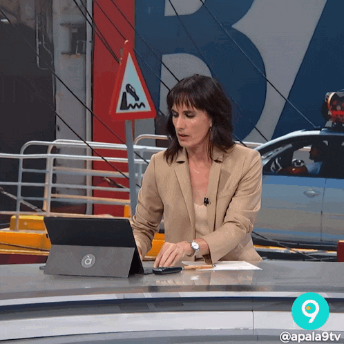 a woman sitting at a desk with a laptop and a sign that says ' lm ' on it