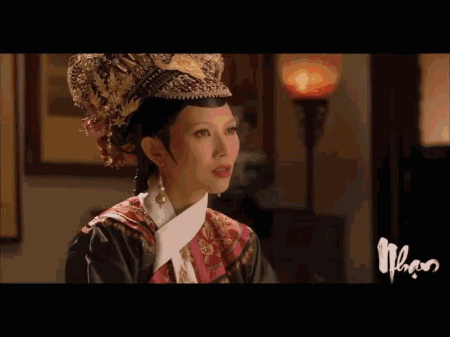 a woman with a crown on her head is sitting in front of a lamp and a sign that says nhan