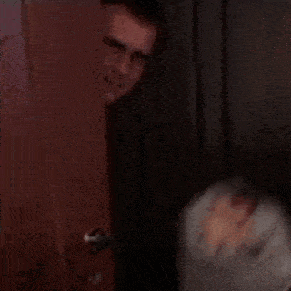 a man is standing in front of a door with a ghost wrapped in plastic .