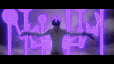 a man is standing in front of a purple wall with his arms outstretched and a purple light behind him .