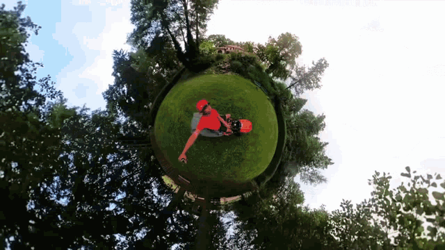 a person in a red shirt is laying on the grass in a circle surrounded by trees