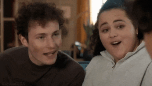 a man and a woman are sitting next to each other in a living room and looking at each other .