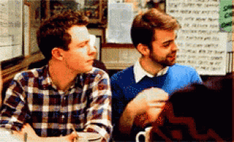 a man in a plaid shirt is sitting at a table with other people