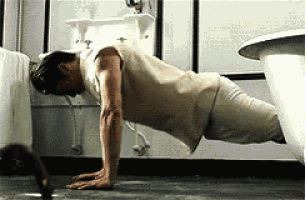 a man is doing push ups on the floor in a bathroom next to a sink .