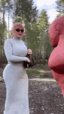 a woman in a white dress is standing next to a man in a red mask .