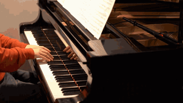 a person playing a piano with a sheet of music behind them