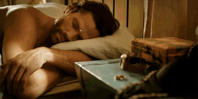 a man is sleeping in a bed next to a suitcase