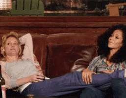 two women sitting on a couch with their feet up