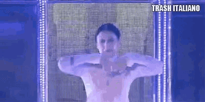a man without a shirt is standing in front of a screen with trash italiano written on it