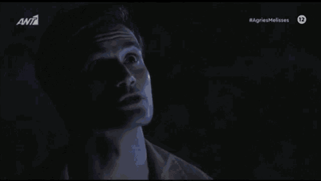 a woman in a white shirt is standing in a dark room in front of a tv screen that says ant on it