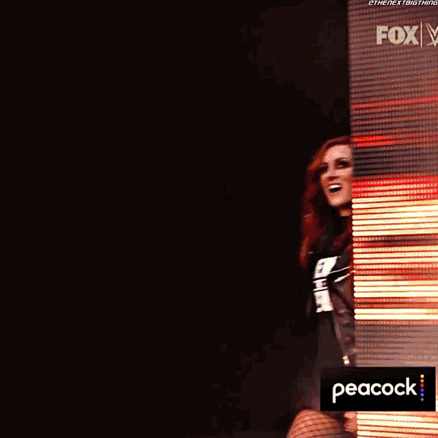 a woman with red hair is standing on a stage in front of a purple and yellow background .