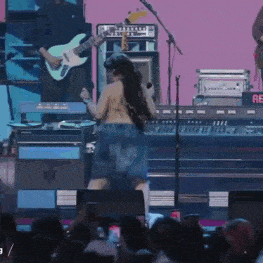a woman is dancing on stage while a man plays guitar