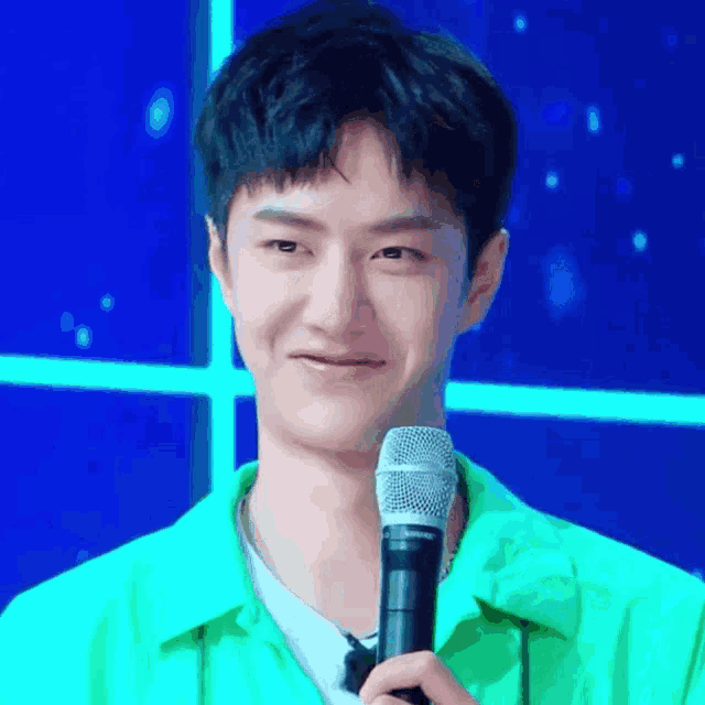 a young man in a green shirt holds a shure microphone