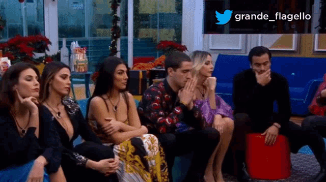 a group of people are sitting on a couch with a twitter logo behind them that says grande flagello