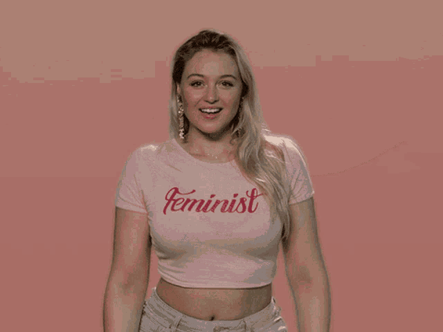 a woman in a pink shirt that says feminist