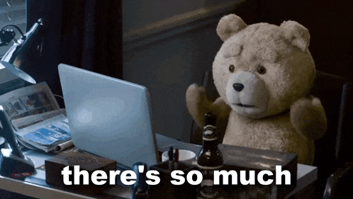 a teddy bear is sitting at a desk with a laptop and the words there 's so much behind him