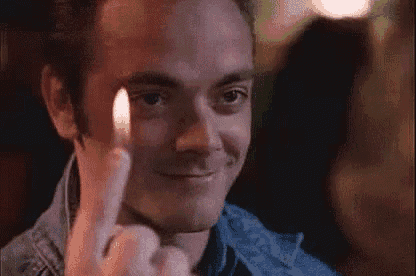 a man is holding a lighter in front of his eye and making a face .