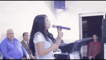 a woman singing into a blue microphone in front of a crowd