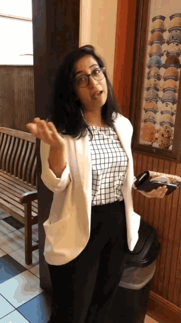 a woman wearing glasses and a white jacket is holding a plate