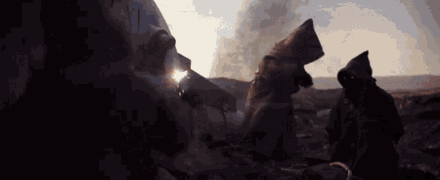 a man in a hooded robe is standing in a dark area
