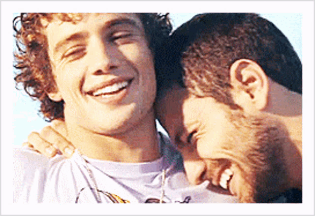 two men are hugging each other and smiling for a photo