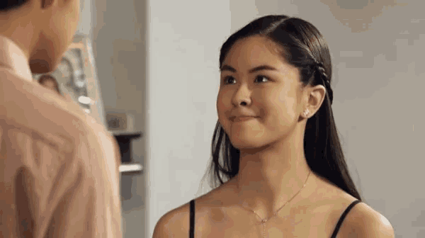 a woman in a black tank top is smiling at a man