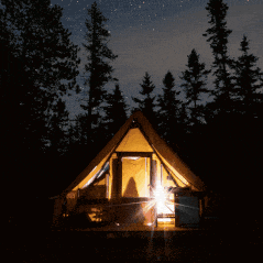 a tent is lit up in the middle of a forest