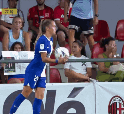 a woman holding a soccer ball in front of a banner that says acm on it