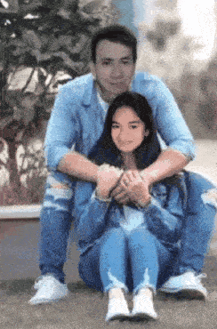 a man is sitting next to a girl who is sitting on the ground with her legs crossed