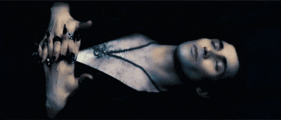 a man is laying down with his eyes closed and a necklace around his neck