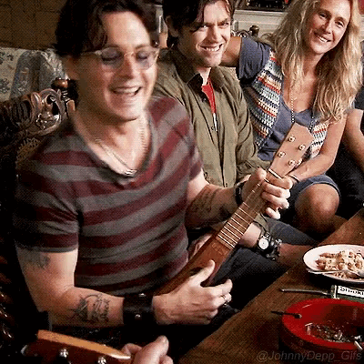 a man is playing a guitar while a woman watches