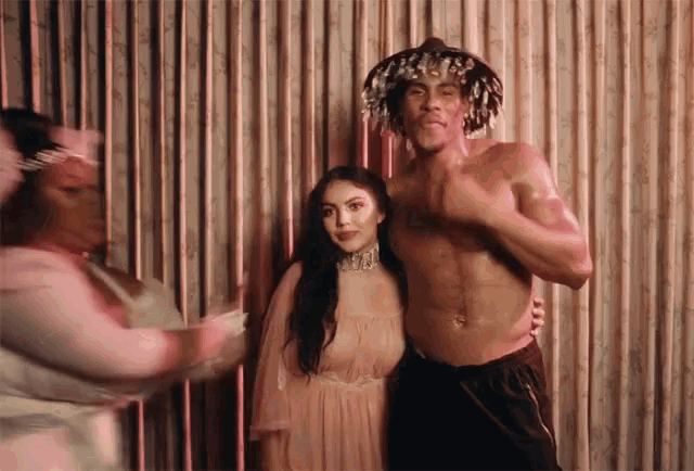 a man without a shirt is standing next to a woman